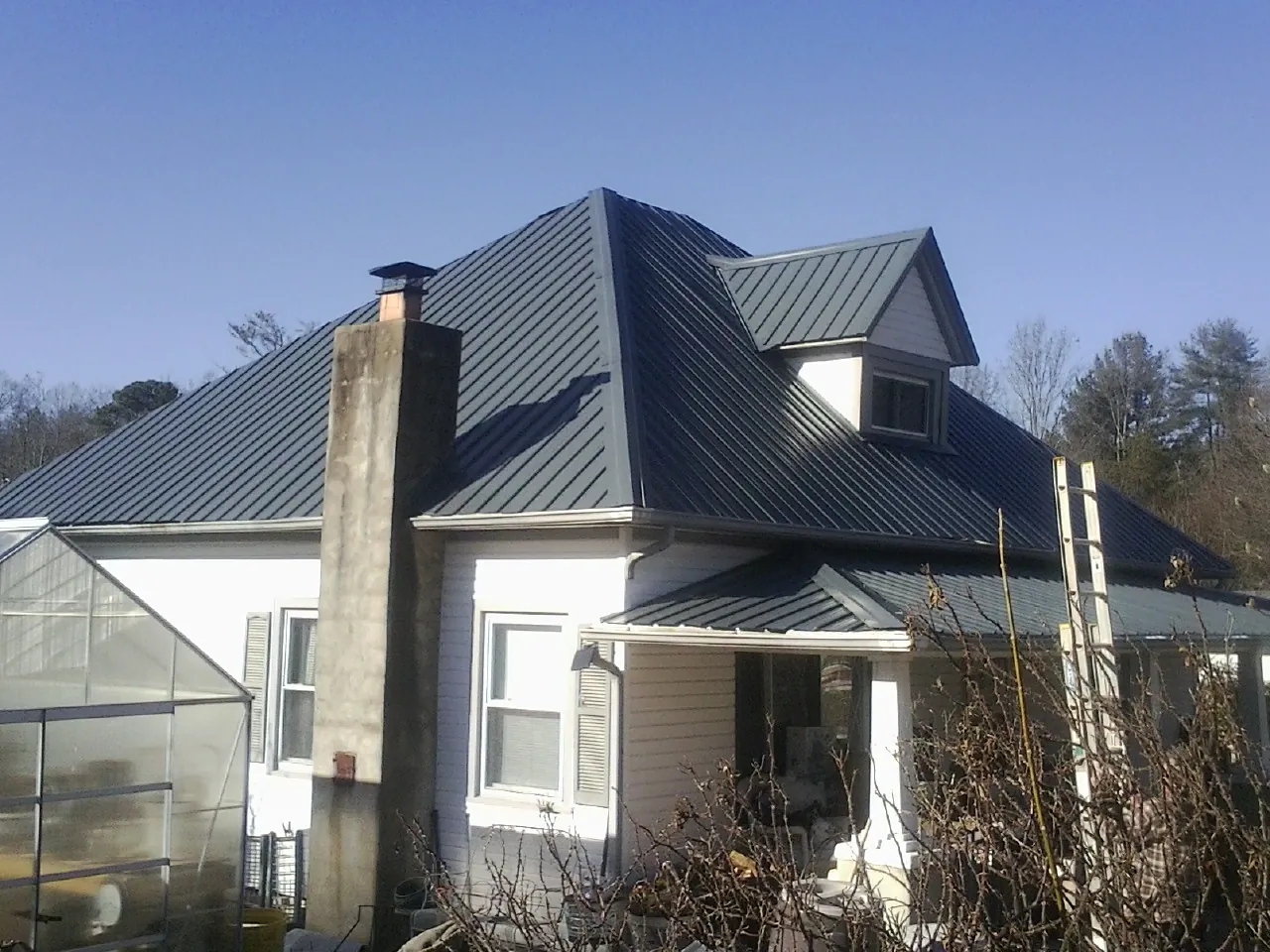 Dark blue standing seam metal roof on a white farmhouse with dormer — Slate & Tile Roof Repair by Roofing Brothers in Biddeford