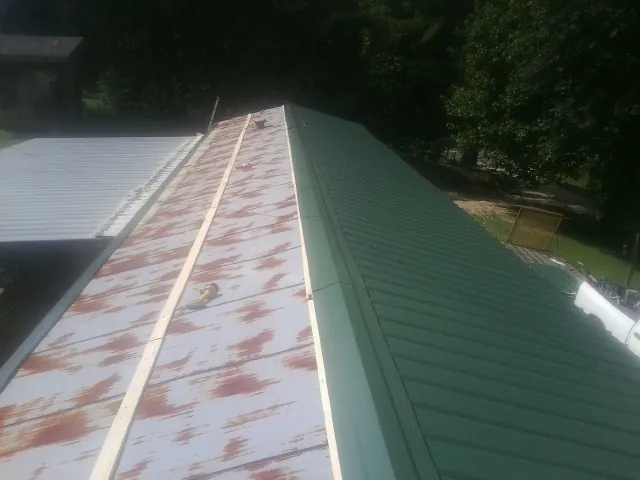 Old rusted panels beside newly installed green metal roofing — Wind Damage Roof Repair by Roofing Brothers in Biddeford