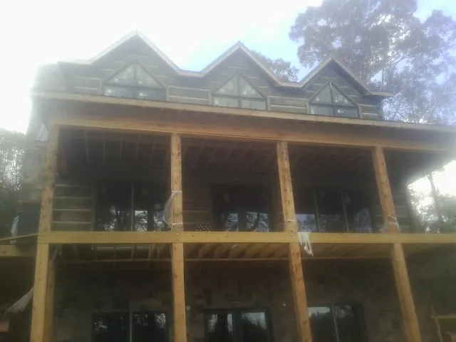 Dormers and porch framing on a large log home under construction — Roof Coating work by our crew in Biddeford