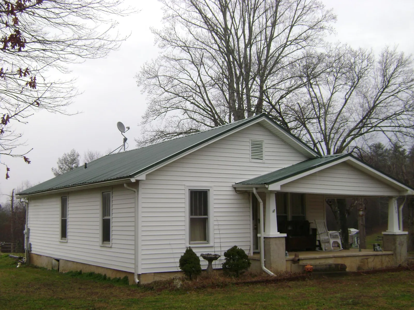 Green metal roof on a white bungalow with a side porch in Biddeford