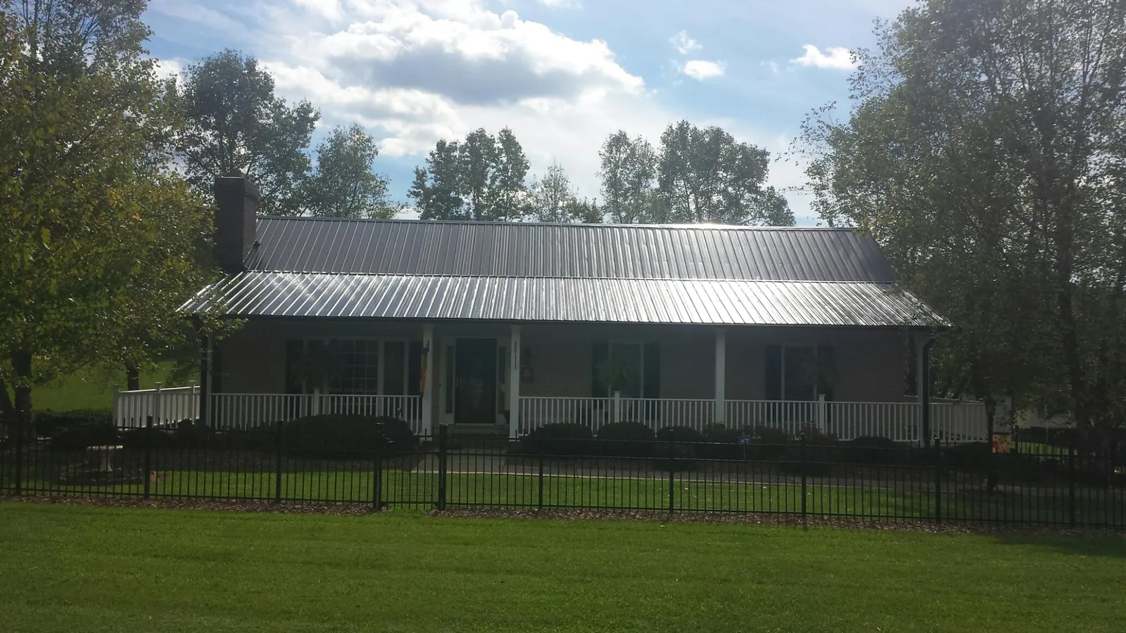 Gray metal roof on a brick ranch with a full width front porch — Gutter Guard Installation work by our crew in Biddeford