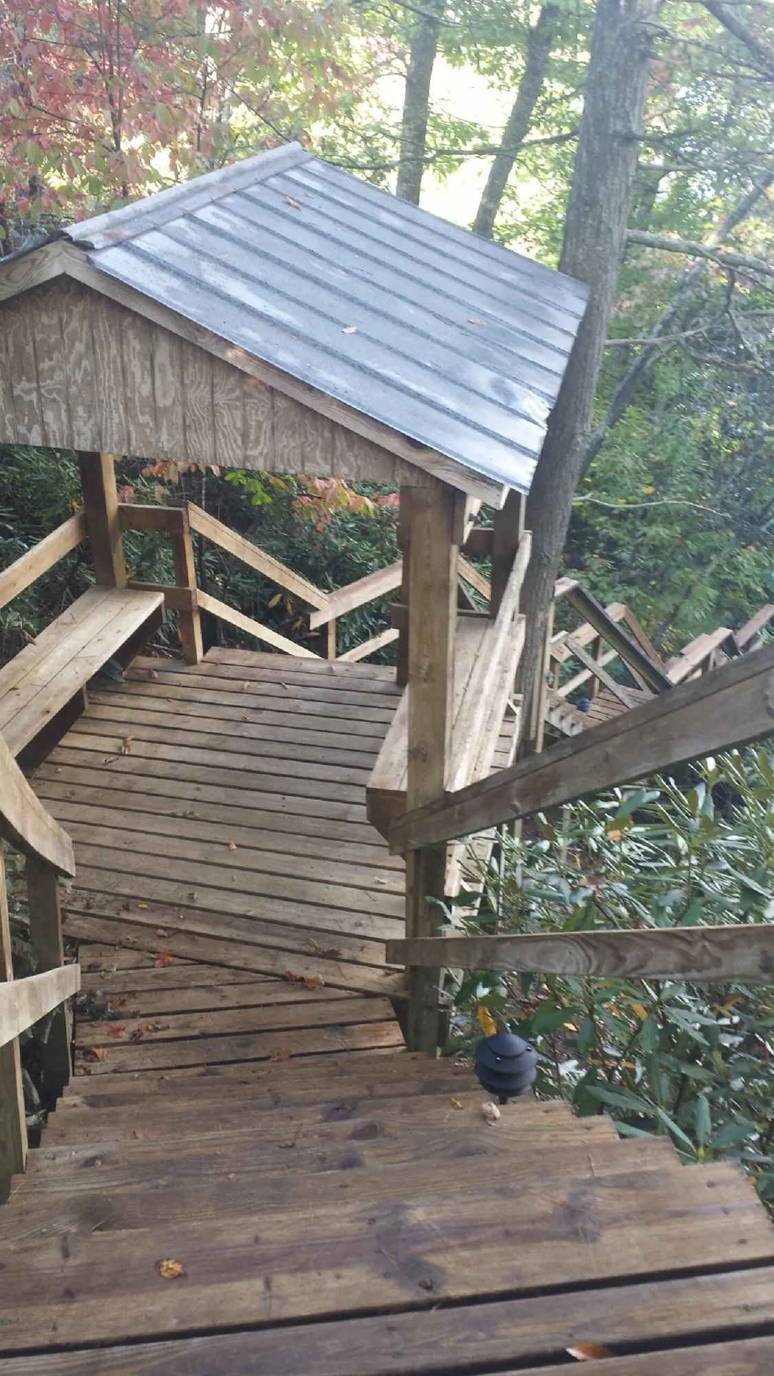Metal roofed shelter over wooden steps on a wooded walkway — Skylight Repair & Installation work by our crew in Biddeford