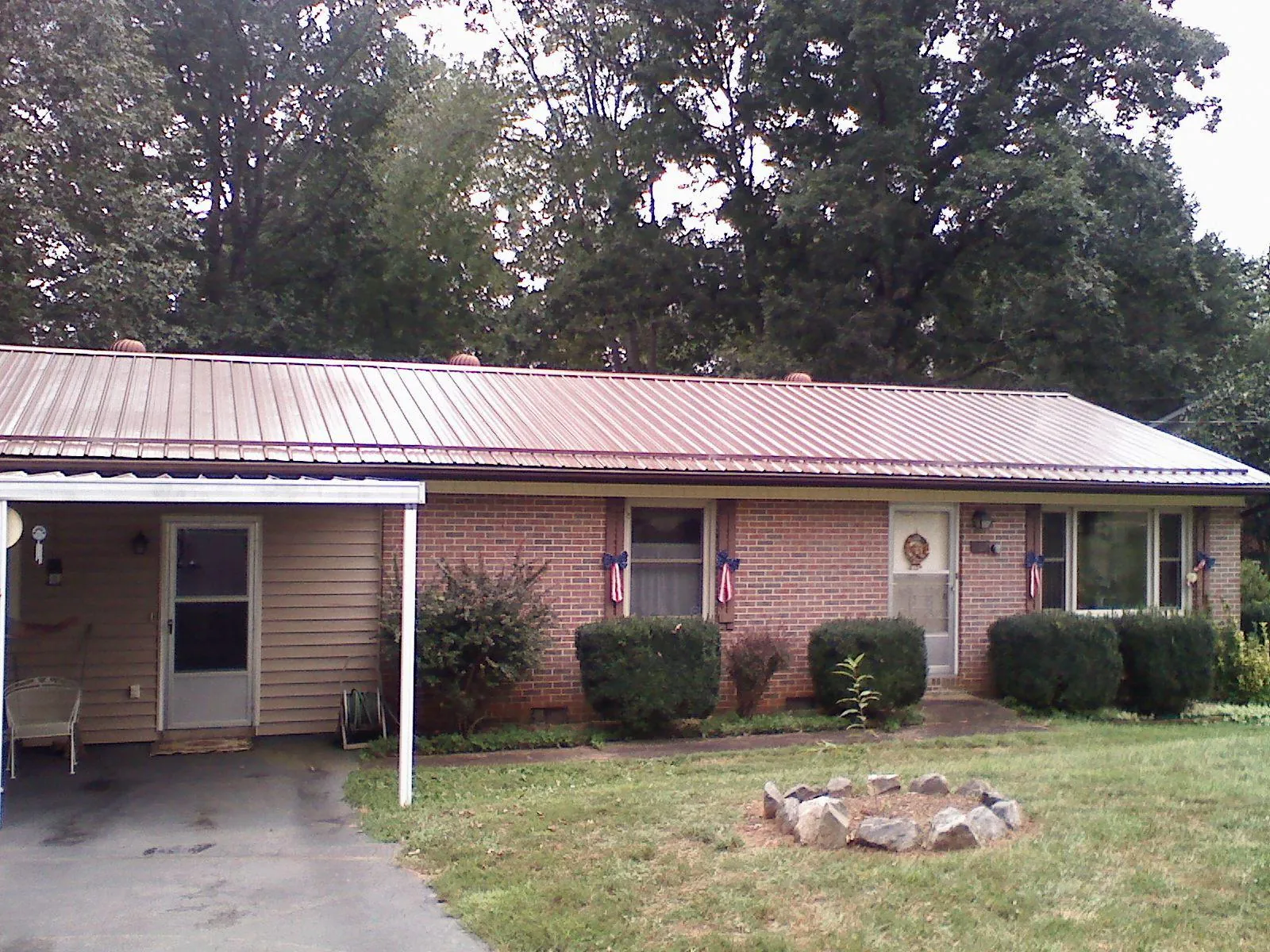 Bronze metal roof and carport on a brick ranch home — Roof Repair work by our crew in Biddeford